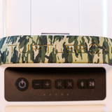 Portable speaker with a camouflage-patterned top and control buttons on the front.