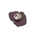 Purple flower-shaped lapel pin with a metal fastener.