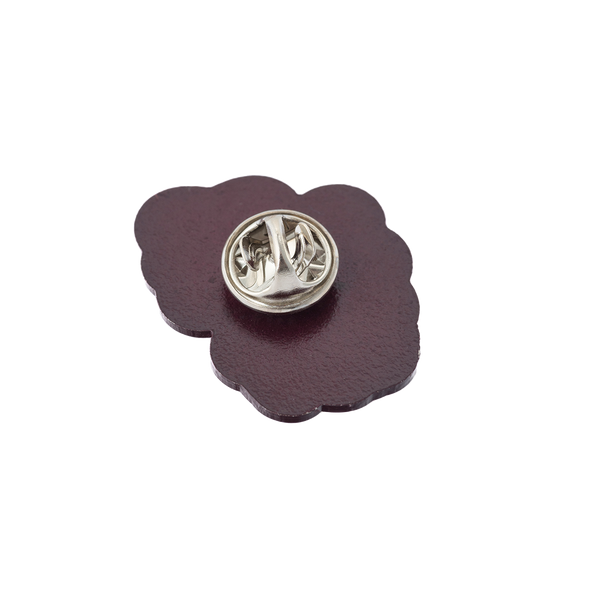 Purple flower-shaped lapel pin with a metal fastener.