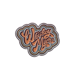 Retro-style enamel pin or patch featuring the text ’Washed Ashore’ in groovy, multi-layered lettering.