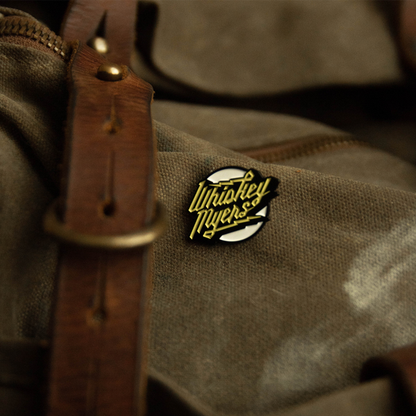 Circular enamel pin with ’Whiskey Myers’ text in yellow and white.